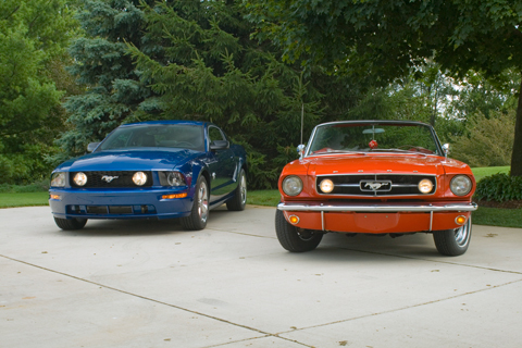 An image of a modern Mustang ext to a first generation Mustang.